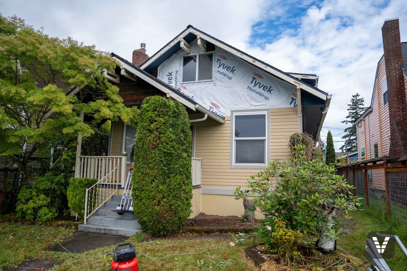 Mid tear-off — Tyvek HomeWrap going on above while the original siding waits below