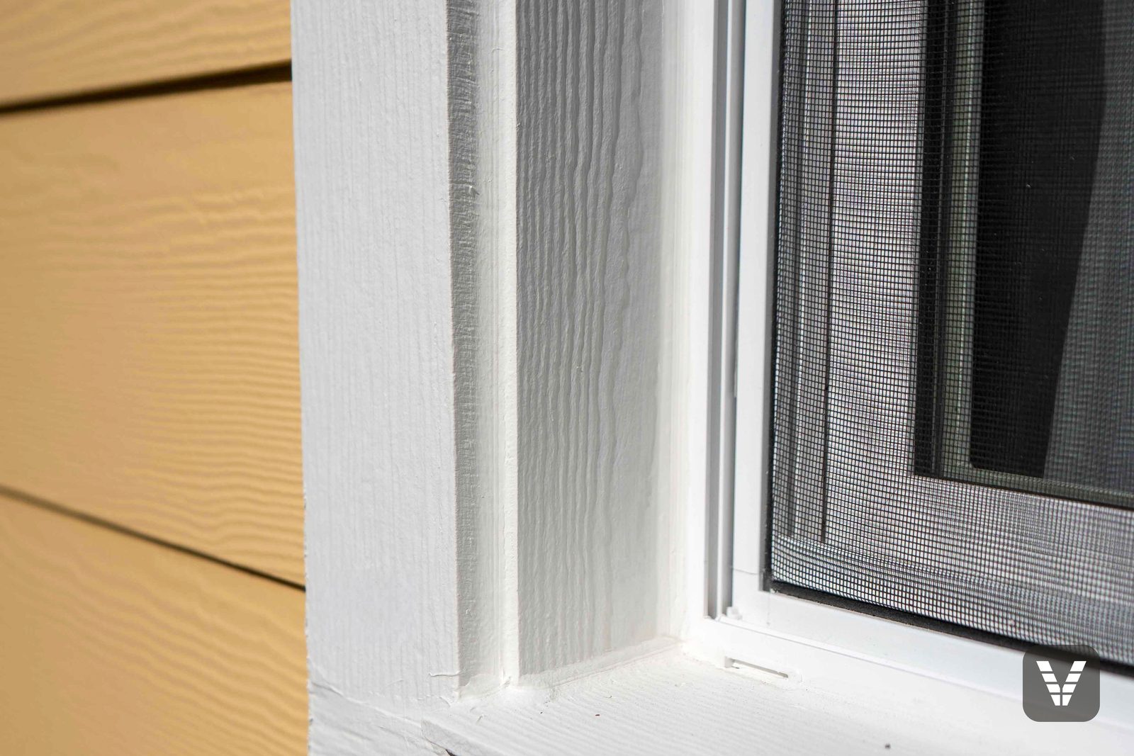 Window trim up close — Cedarmill-textured HardieTrim surrounds and a new sill line, painted crisp white against the yellow lap — Siding & Window Vault project in Bellingham, WA
