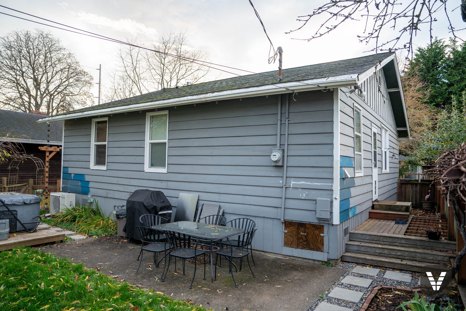 Backyard before — asbestos-cement siding with paint-sample patches — before, Bellingham, WA