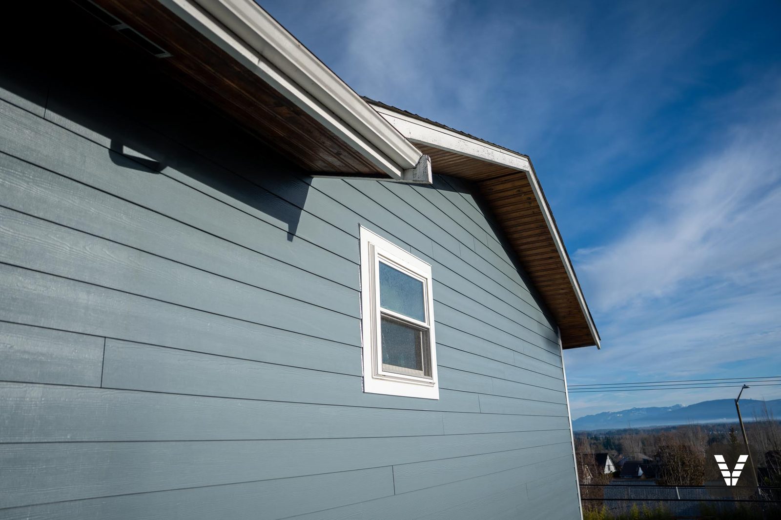 The gable end over the valley — stained wood soffits preserved above the new lap — Siding & Window Vault project in Ferndale, WA