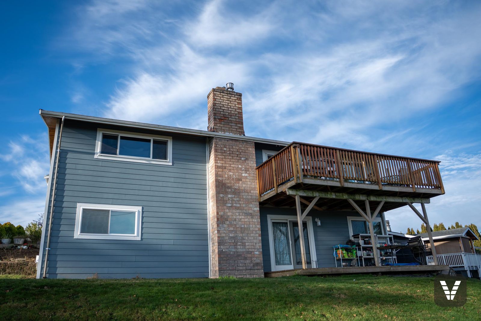 The rear elevation — Boothbay Blue against the brick chimney and the upper deck — Siding & Window Vault project in Ferndale, WA