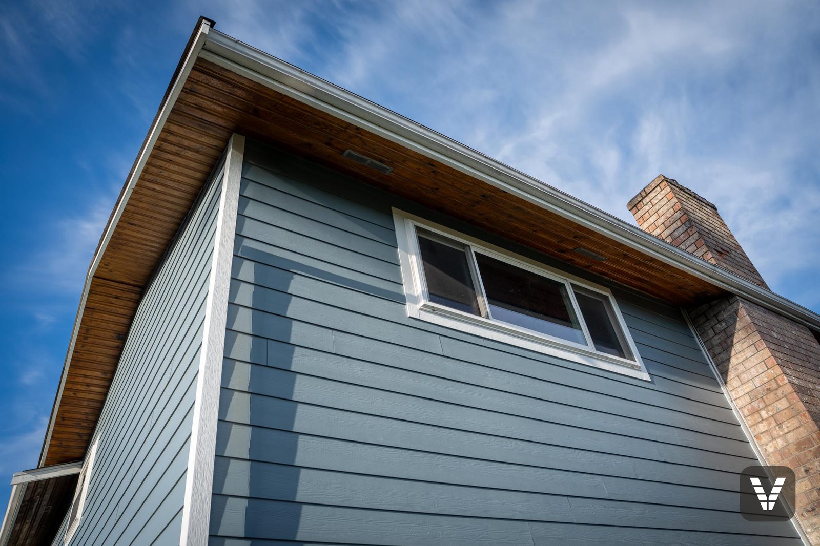 Under the eaves — the preserved stained-wood soffit against new lap and trim