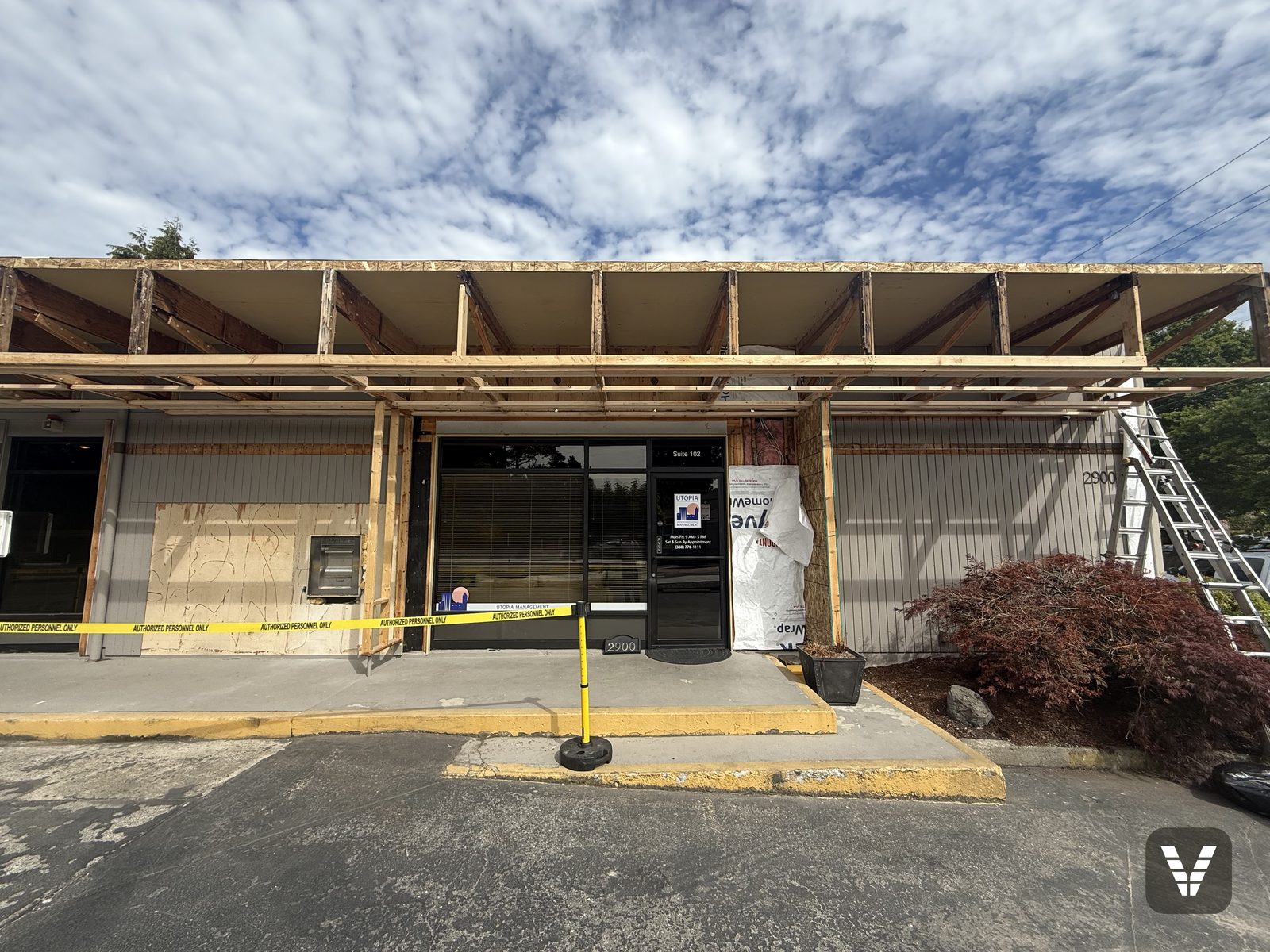 The original overhang stripped to its framing, with the work zone taped off so the offices stayed open