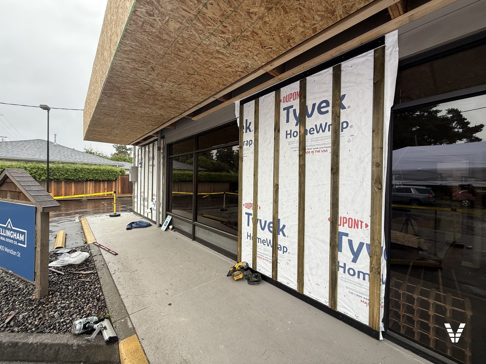 Pressure-treated furring going up over the weather barrier — the rain-screen assembly that let fiber cement attach to concrete