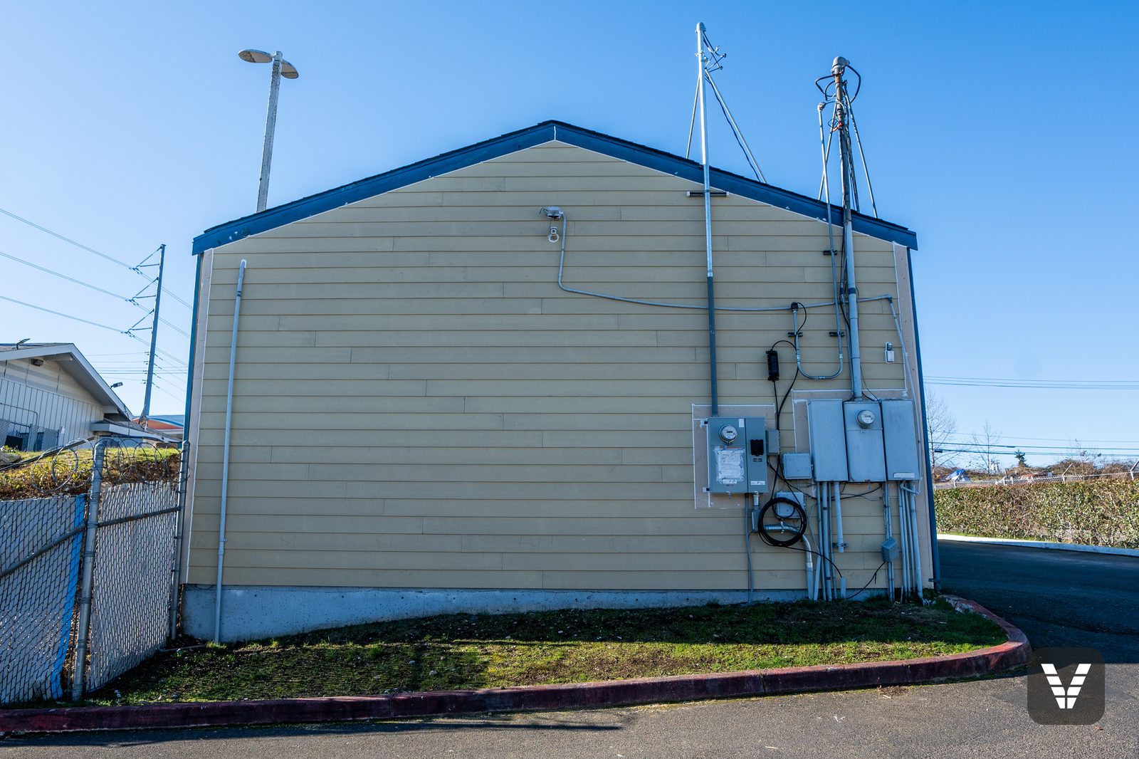 A gable end in fresh primed lap, service mast and floodlights remounted