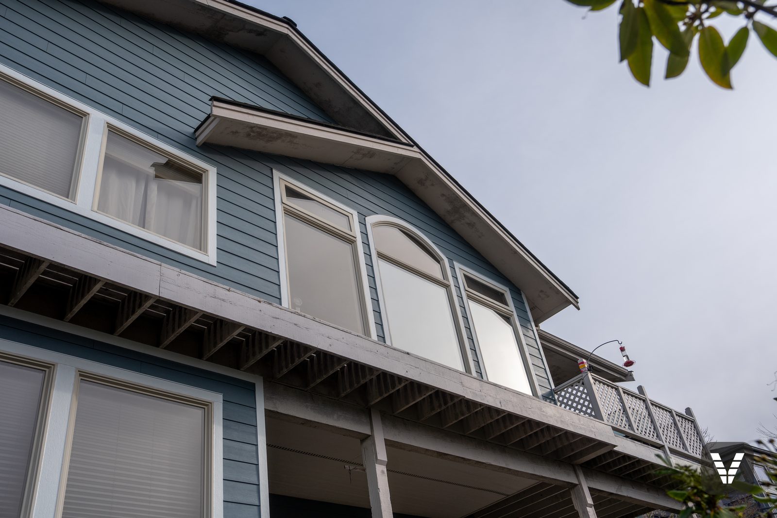 Looking up at the rear gable — new siding below, the original deck beam and eaves above, left for the painter by the owners' choice