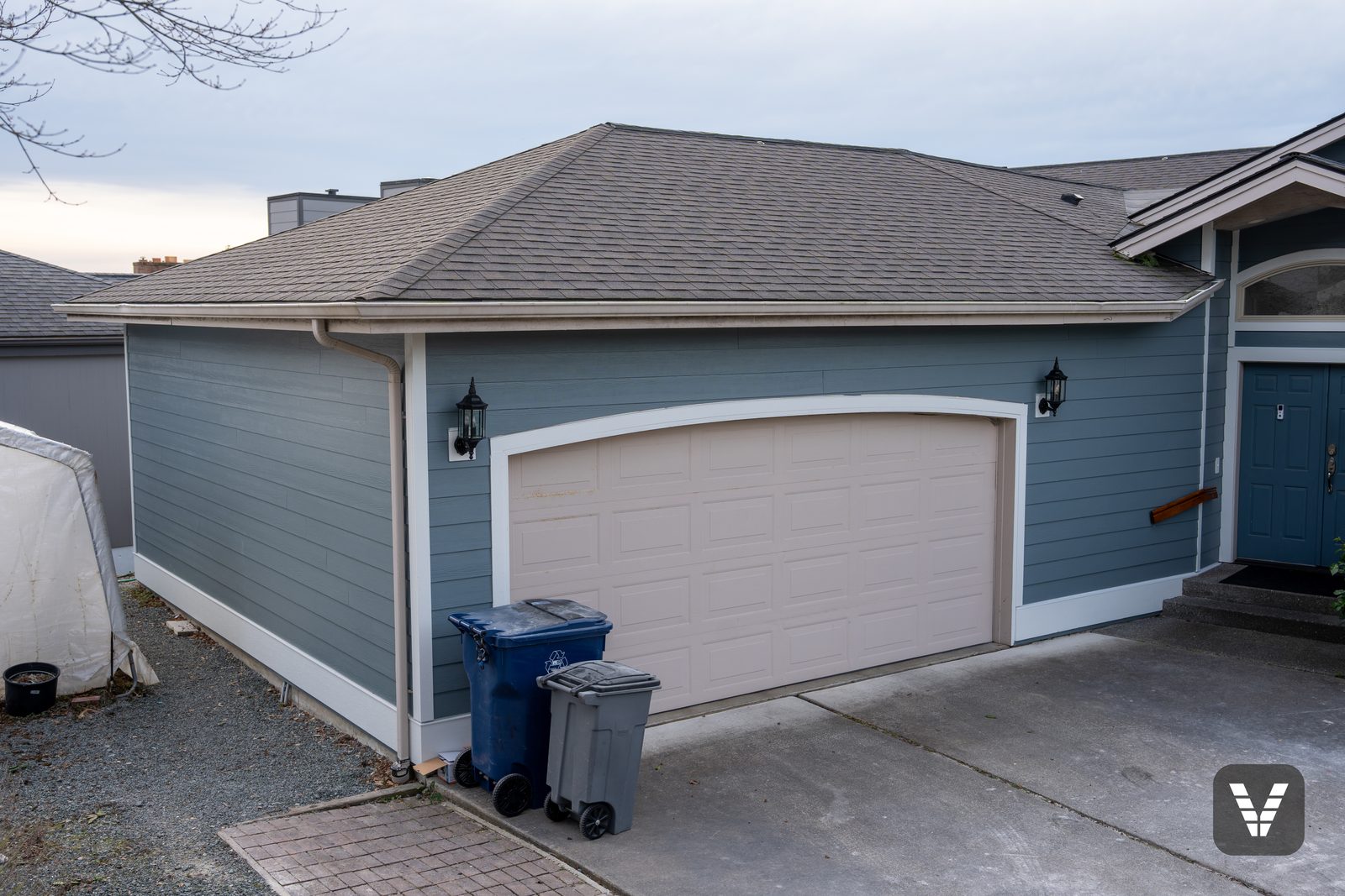The garage corner — new lap and arch trim around the original garage door, kept as-is by the owners