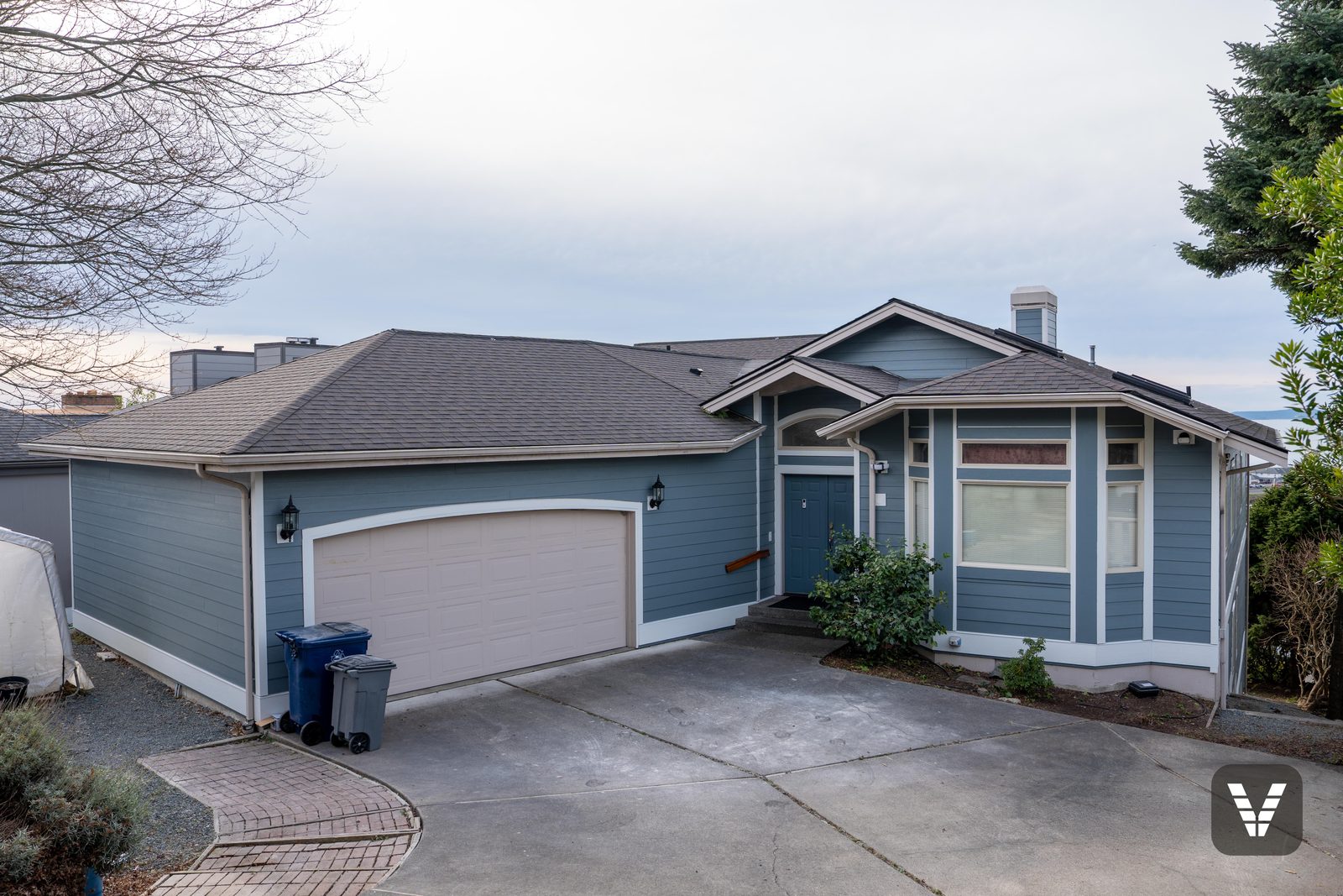 Completed Boothbay Blue James Hardie re-side with Arctic White band boards on an Anacortes hillside home above the marina — Siding & Window Vault project in Anacortes, WA