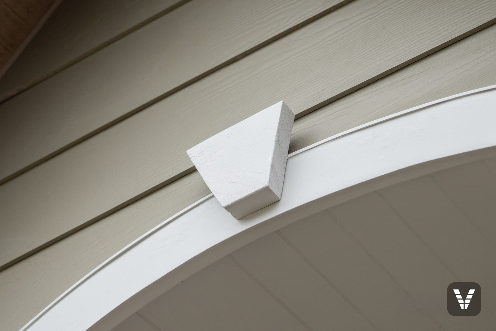 The heat-formed AZEK arch — one continuous piece of PVC trim curved over the entry, keystone seated on top, no seams anywhere — Siding & Window Vault project in Anacortes, WA