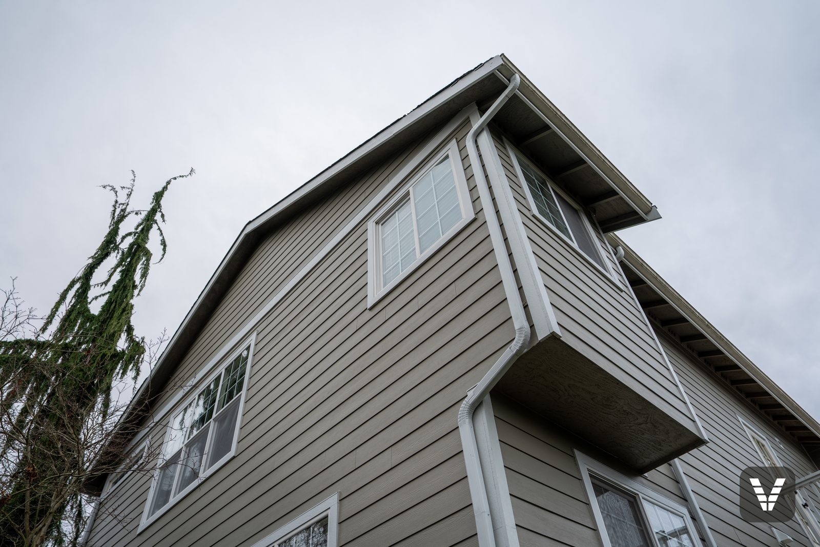 Looking up the corner — clean lap lines, painted eaves, and downspout