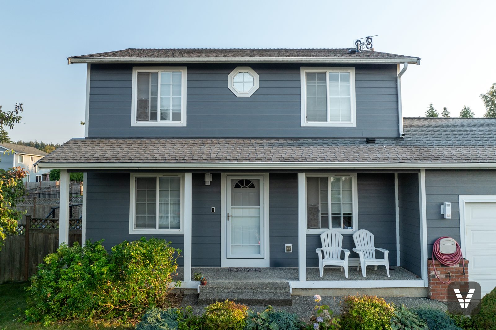 The finished front at golden hour — Night Gray lap, Arctic White trim, and the brick the house kept