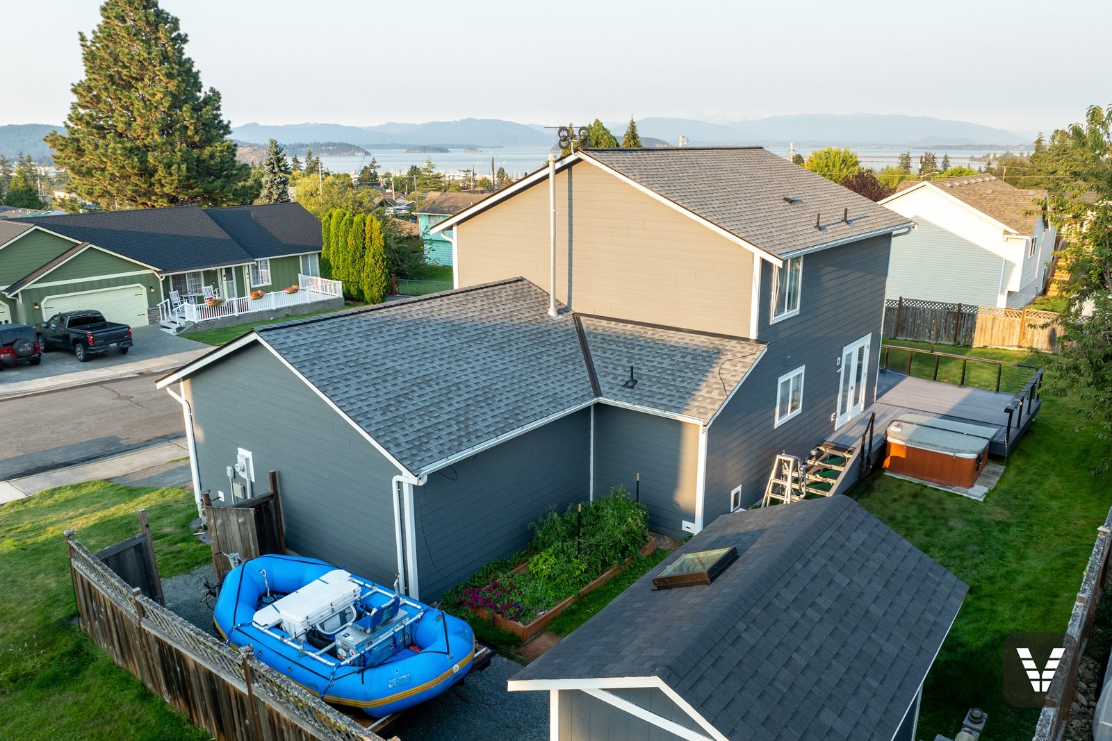 The drone view toward Fidalgo Bay — Night Gray lap, new roofline trim, and the marina on the horizon