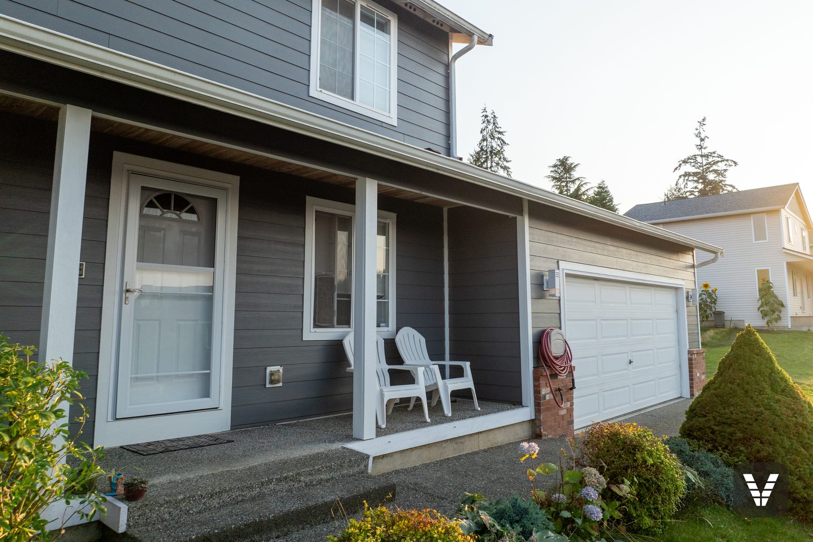 The covered porch and garage wing — Night Gray lap against the original brick accents