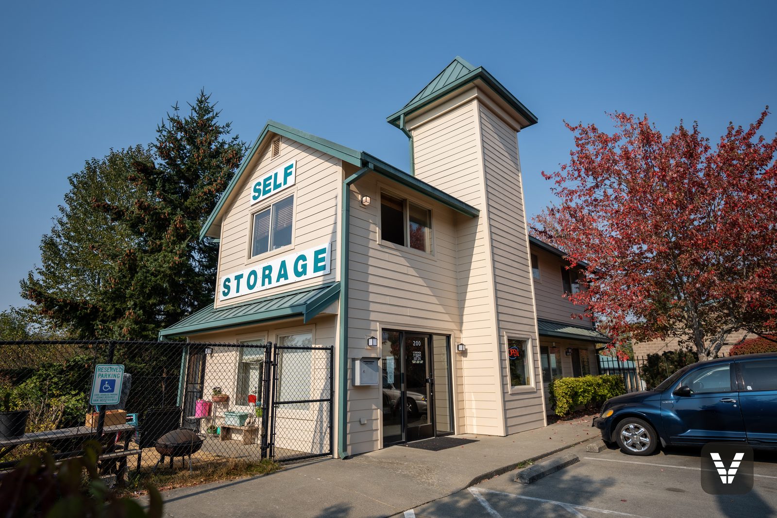 The Cordata Self Storage office and tower after its re-side, painted cream with green accents, red maple beside it
