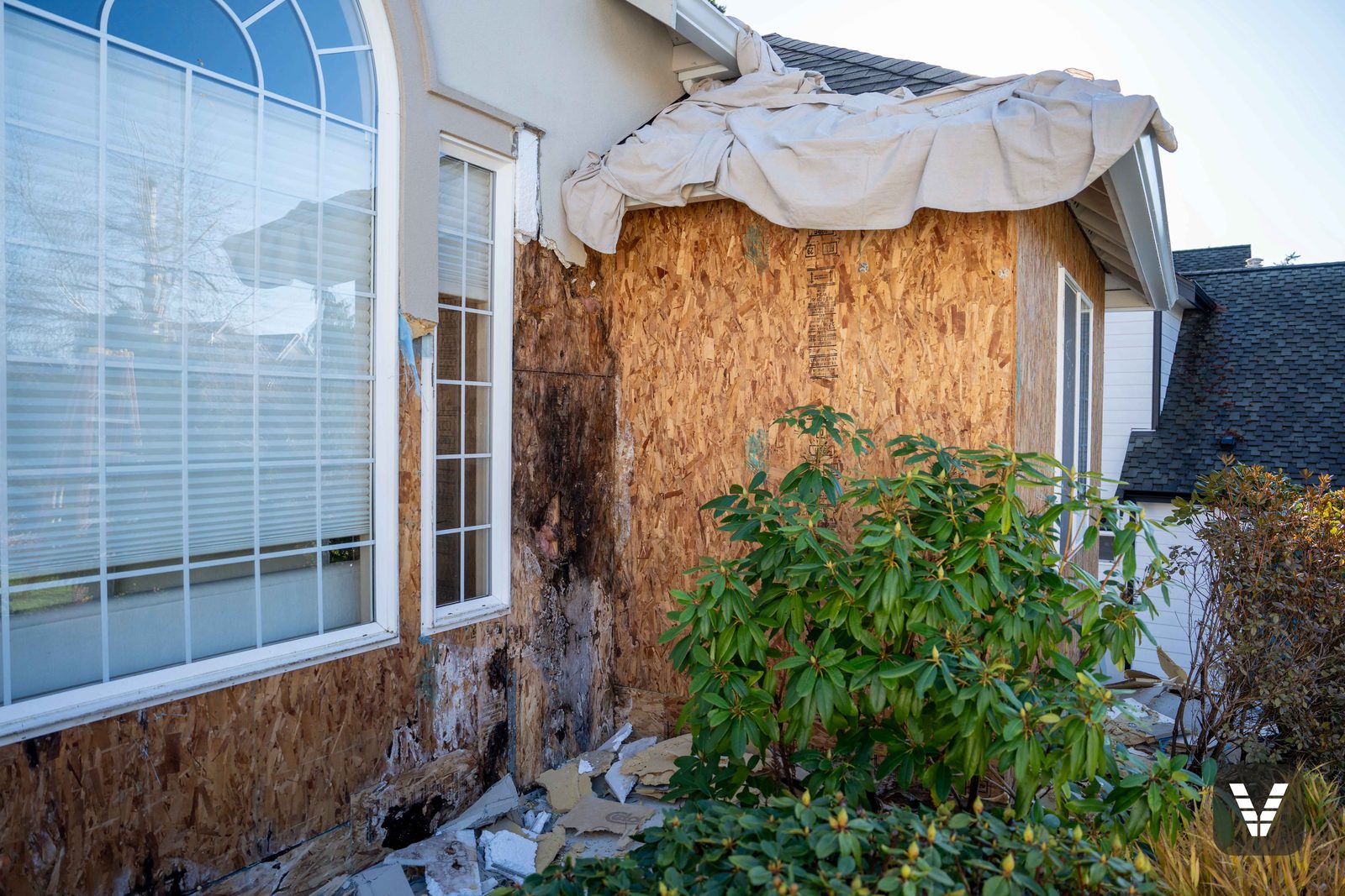 Moisture-damaged sheathing uncovered behind failed stucco during a Bellingham tear-off