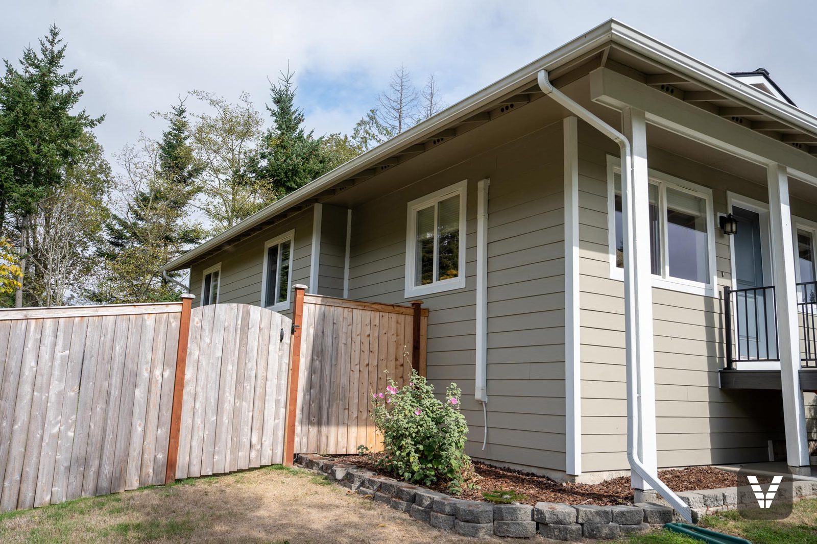 Side windows trimmed in Arctic White along the fence line — Siding & Window Vault project in Anacortes, WA