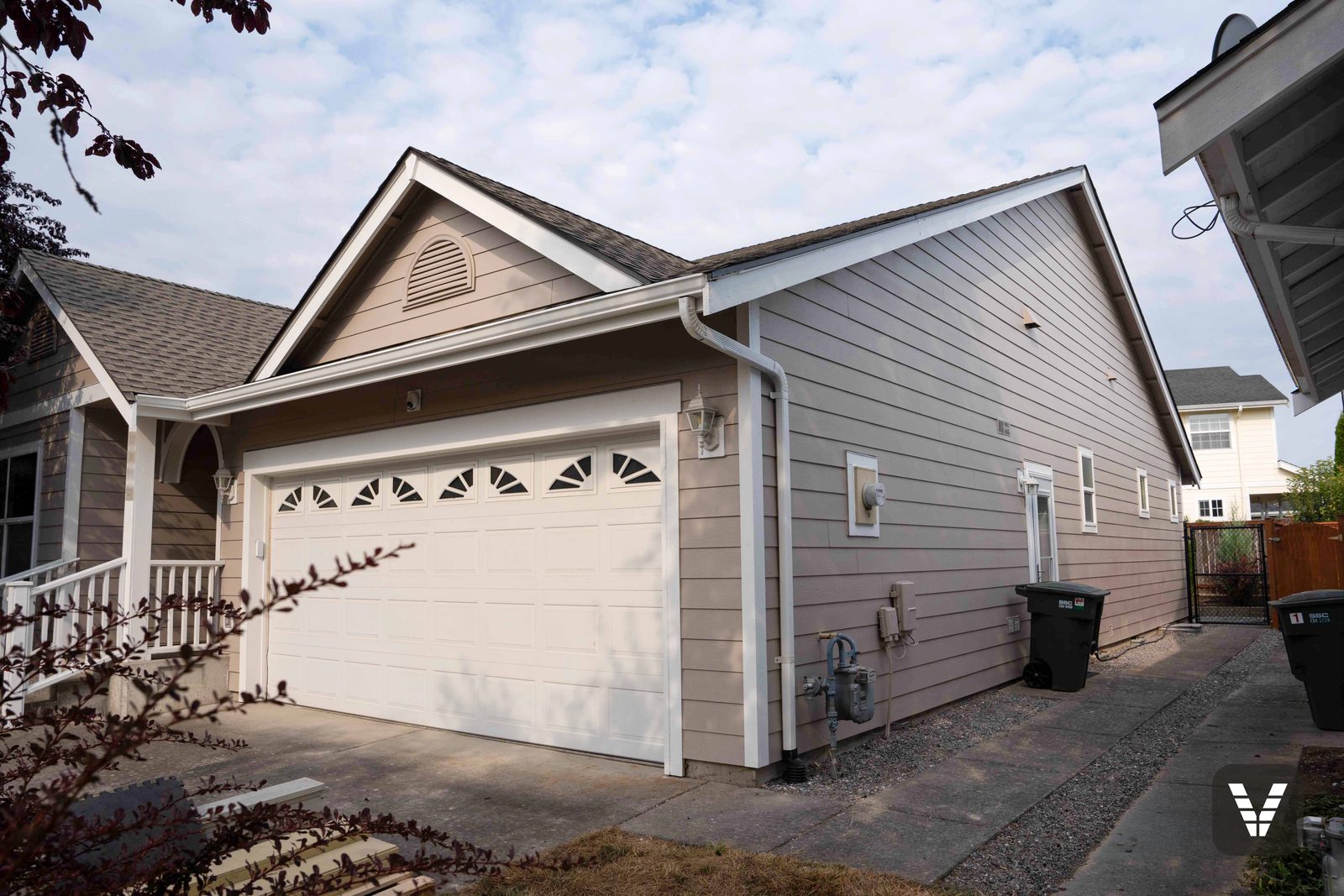 The garage wing and side path — fresh lap, painted gutters, and the lantern sconces back on their new fiber-cement blocks — Siding & Window Vault project in Bellingham, WA