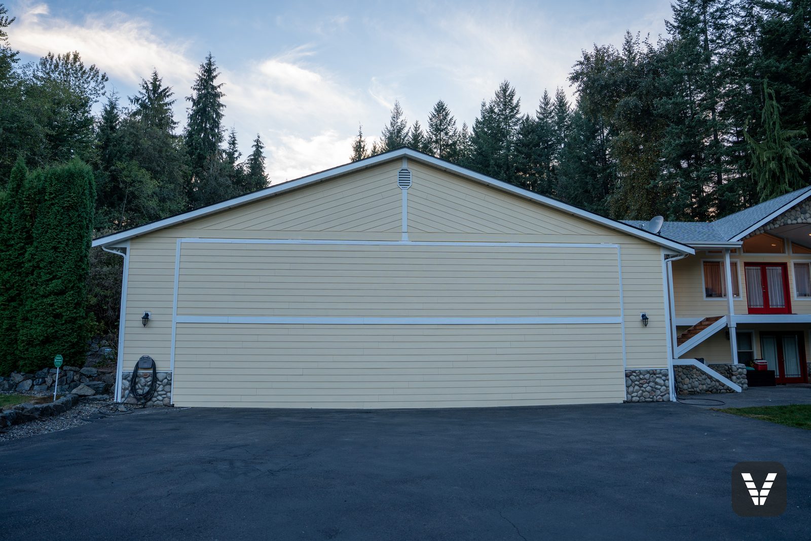 The hangar door wall — one huge working door for the owner's personal plane, wrapped in new HardiePlank and painted to match the house — Siding & Window Vault project in Lake Stevens, WA